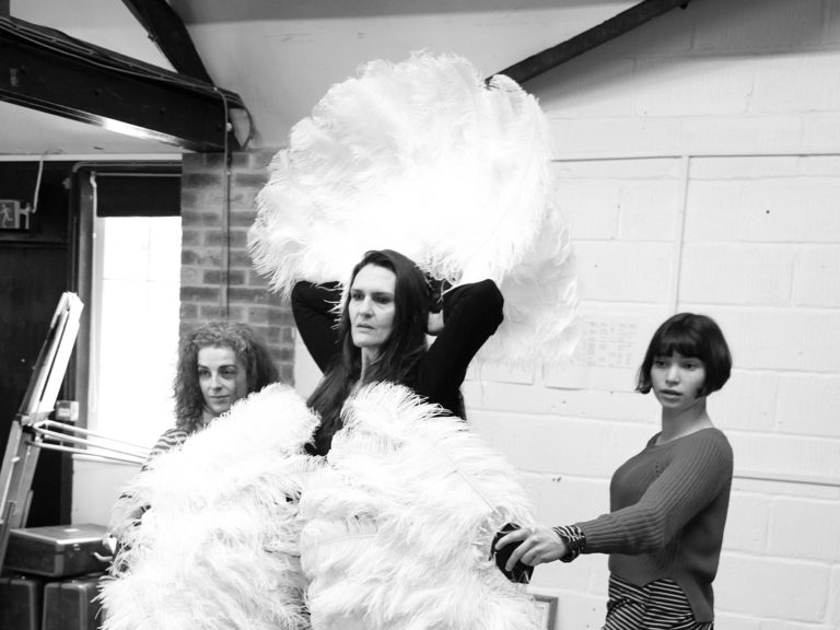A black and white photo of three females rehearsing a burlesque dance