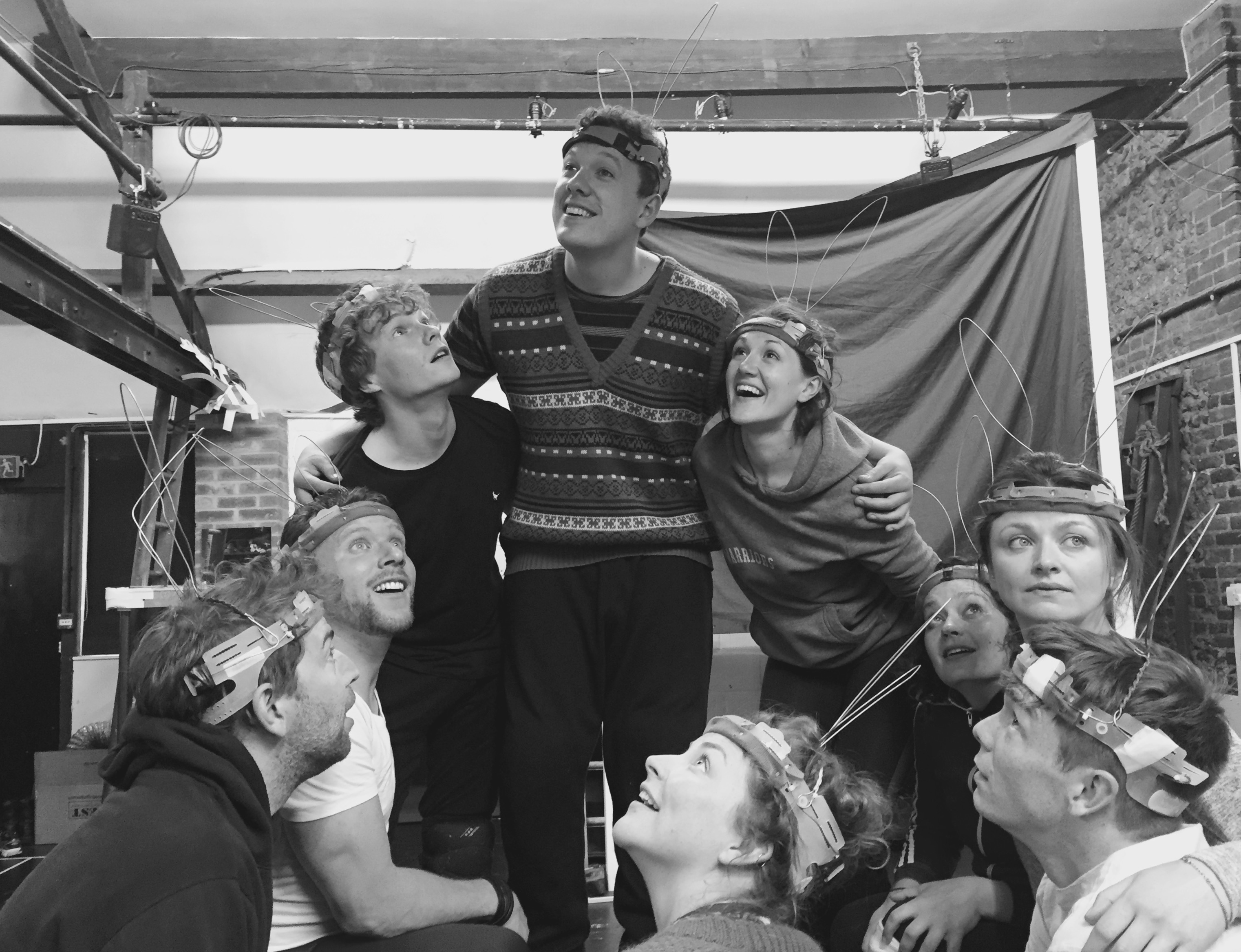 A black and white photo from the rehearsals of Watership Down. The cast are huddled together looking up.