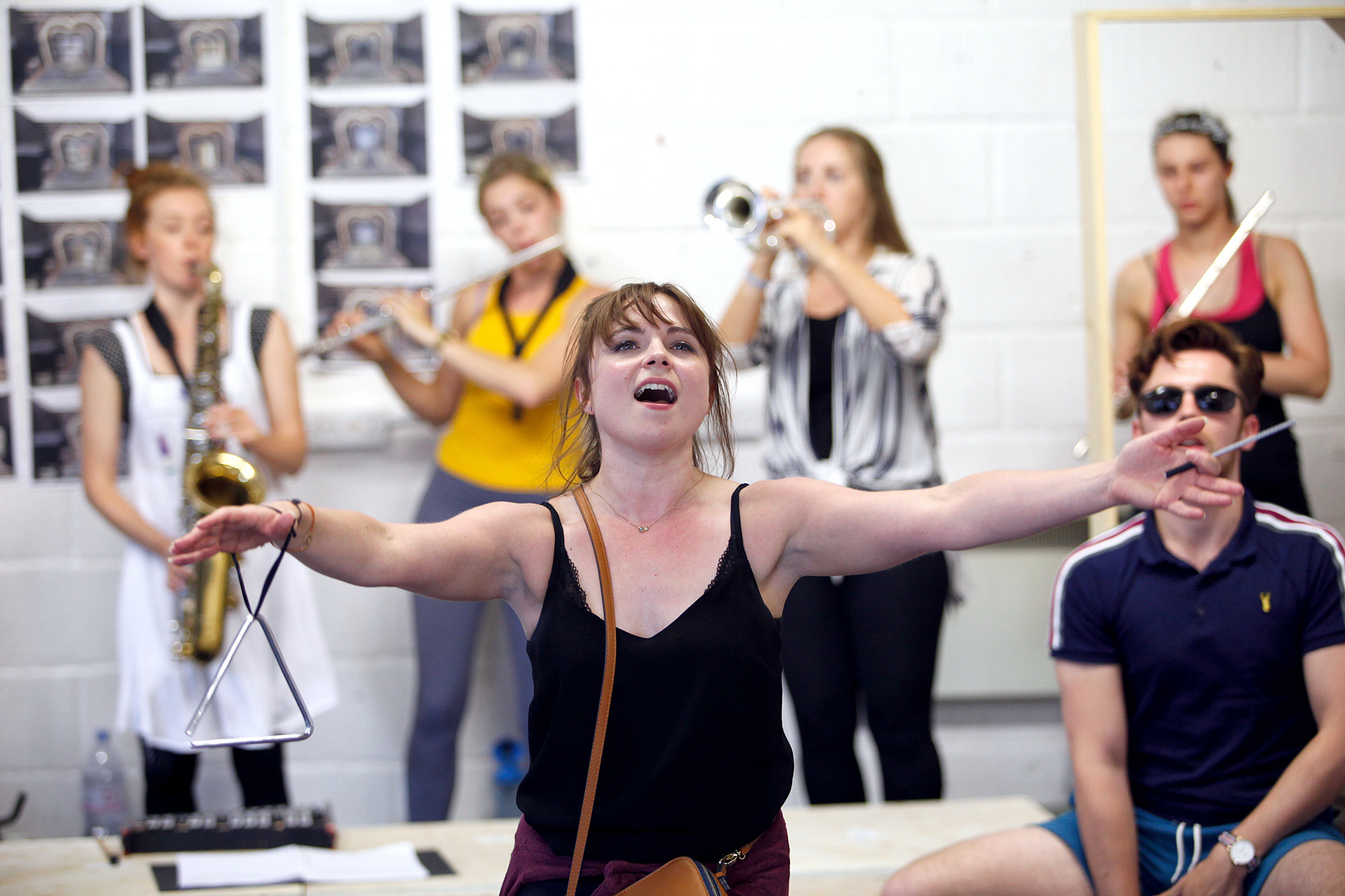 A photograph of Sweet Charities rehearsal. Female has arms outstretched while singing.