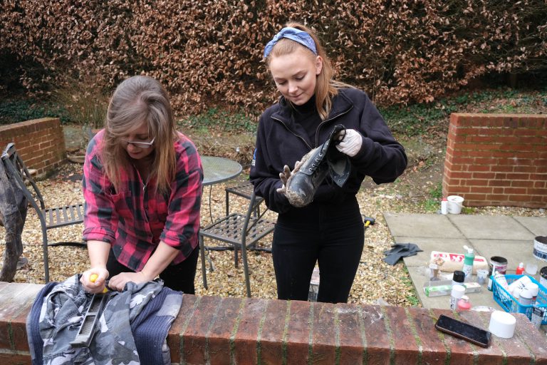A photo of Natalie Toney and Head of Wardrobe Emily Barratt muddying some boots.